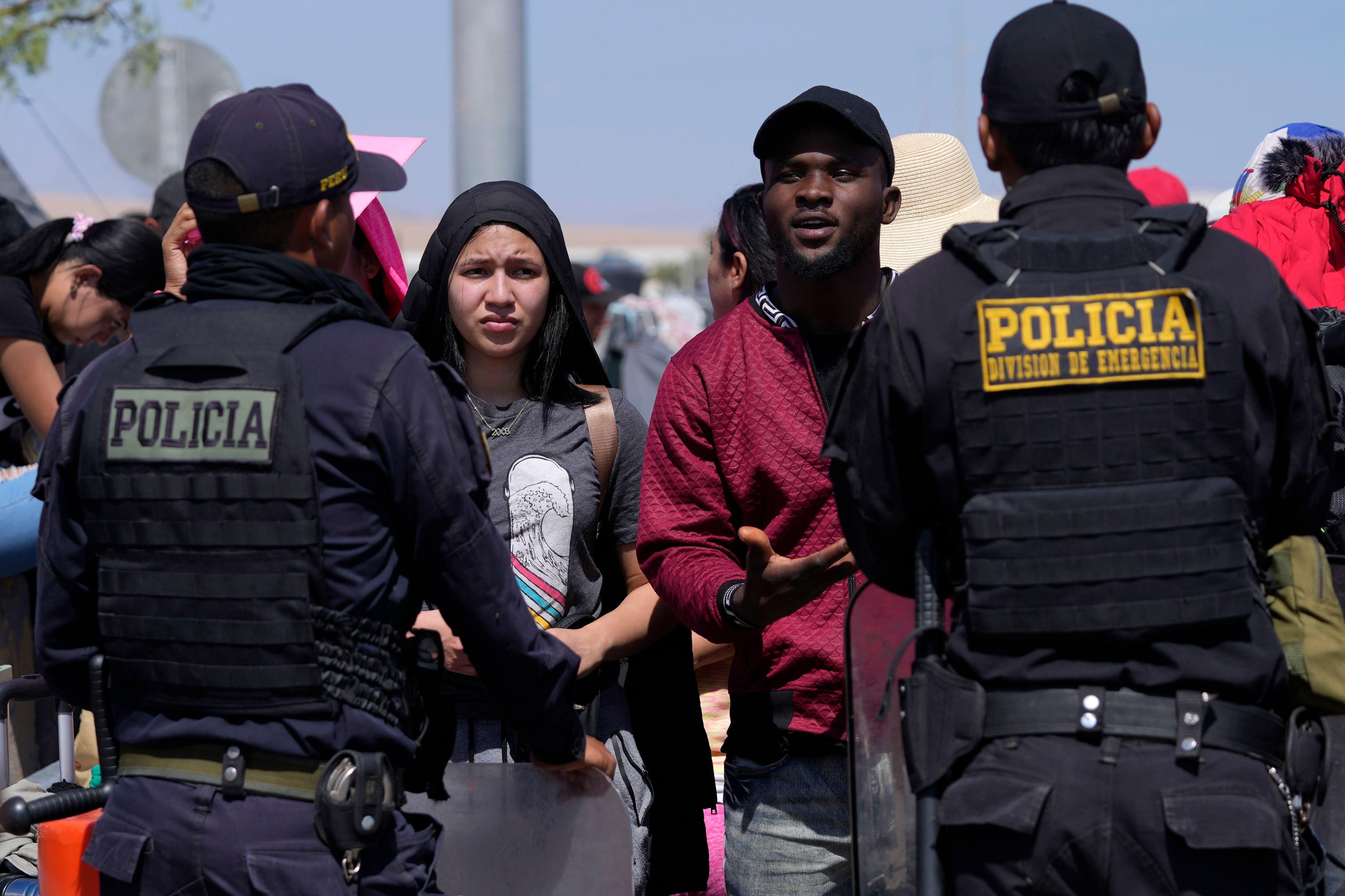 Migrantes venezolanos hablan con agentes de la policía peruana que custodian la frontera con Chile, en Tacna, Perú, el viernes 28 de abril de 2023. (AP Foto/Martín Mejía)