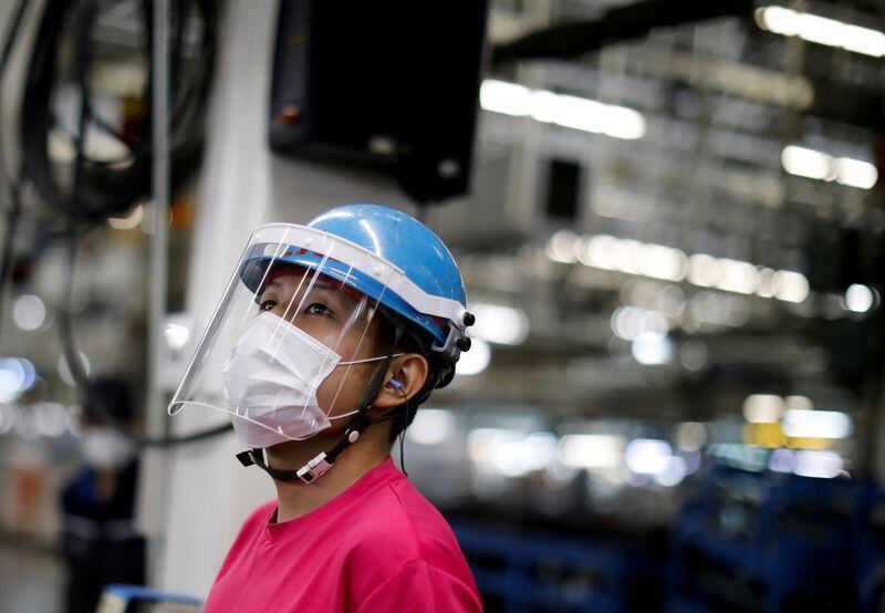 Un operario con barbijo y protector facial trabaja en la línea de montaje