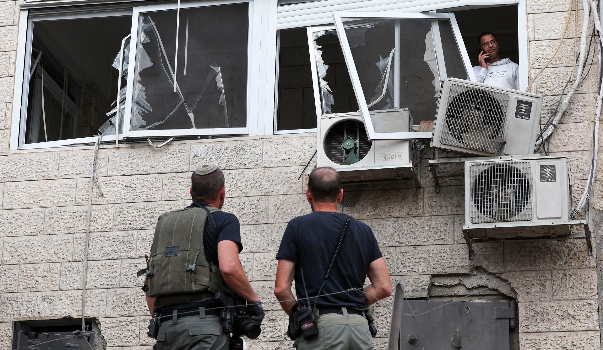 Isreali security forces inspect damage on a building in the Arab-Israeli town of Abu Ghosh near Jerusalem, after a rocket attack from Gaza on October 9, 2023. Stunned by the unprecedented assault on its territory, a grieving Israel has counted over 700 dead and launched a withering barrage of strikes on Gaza that have raised the death toll there to 493 according to Palestinian officials. (Photo by AHMAD GHARABLI / AFP)