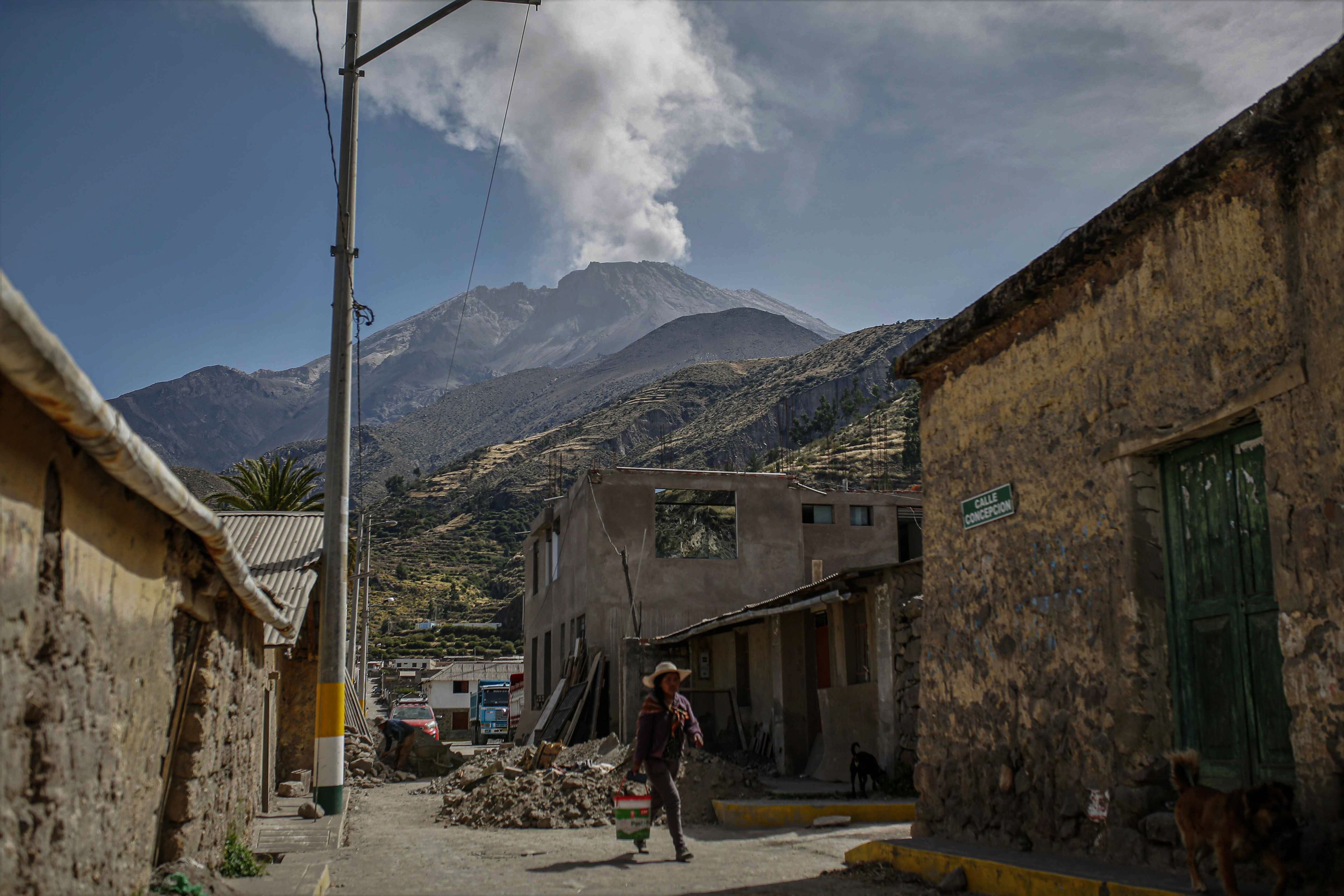 Una persona camina por una calle del pueblo de Ubinas y al fondo se observa el volcán Ubinas, en Moquegua (Perú). EFE/Stringer
