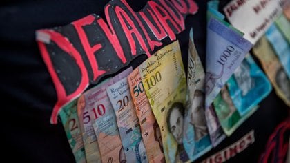 Fotografía de varios billetes de cono monetario venezolanos pegados a un cartel de protesta en Caracas (Venezuela).  Foto: EFE / Miguel Gutiérrez