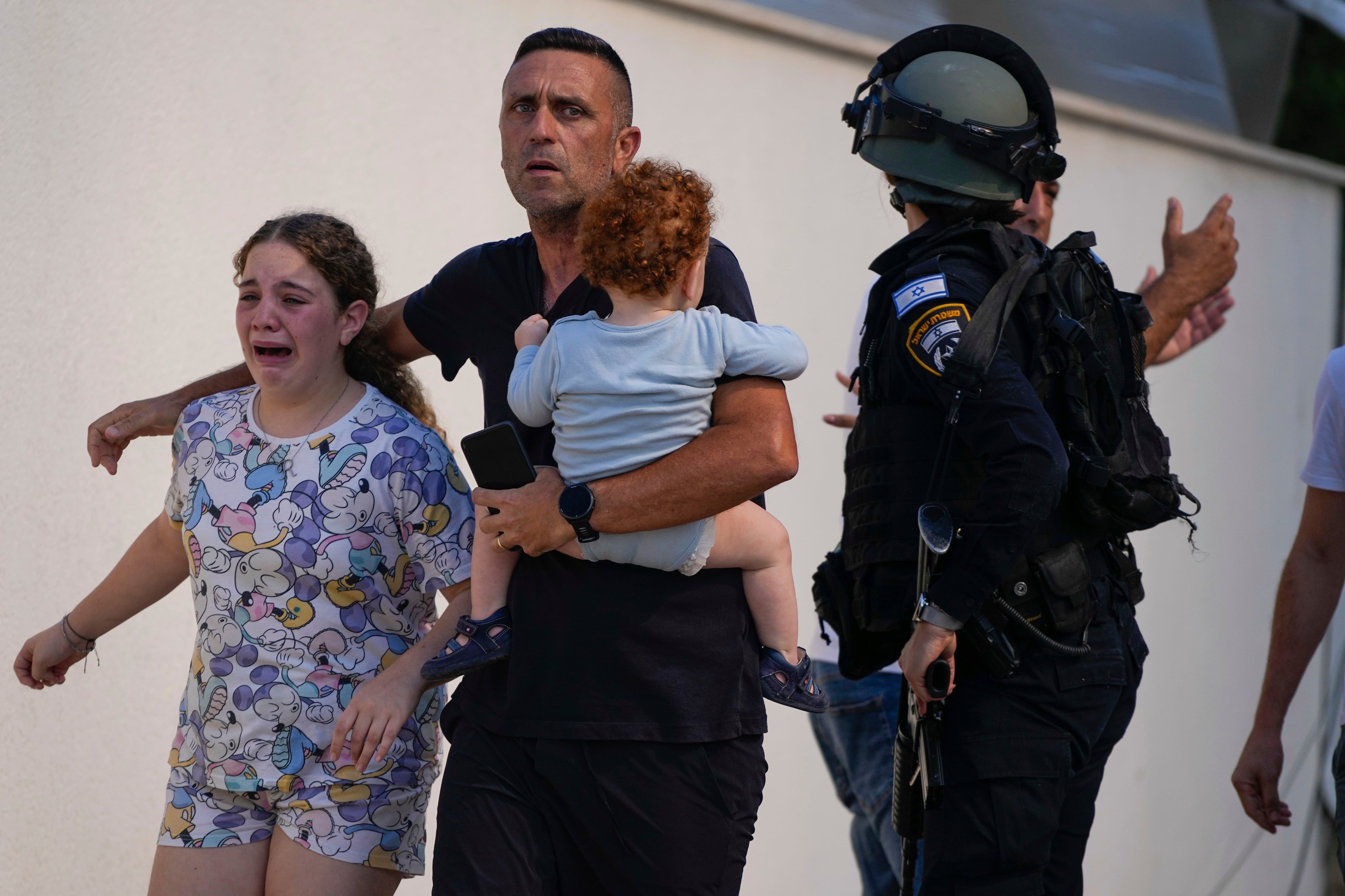 Agentes de policía israelíes evacuan a una familia de un lugar alcanzado por un cohete disparado desde la Franja de Gaza, en Ashkelon, (AP Photo/Tsafrir Abayov)