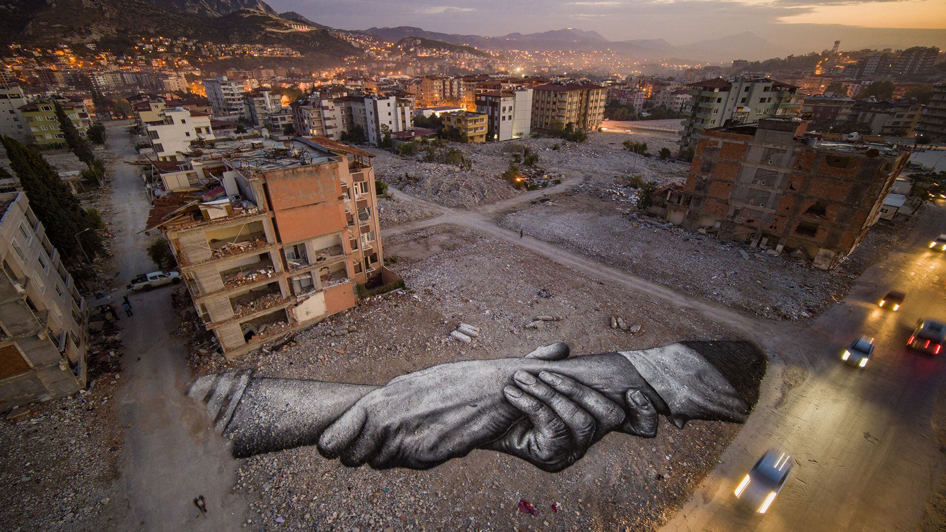 Saype, muestra una pintura landart gigante biodegradable ubicada entre edificios dañados por el terremoto 