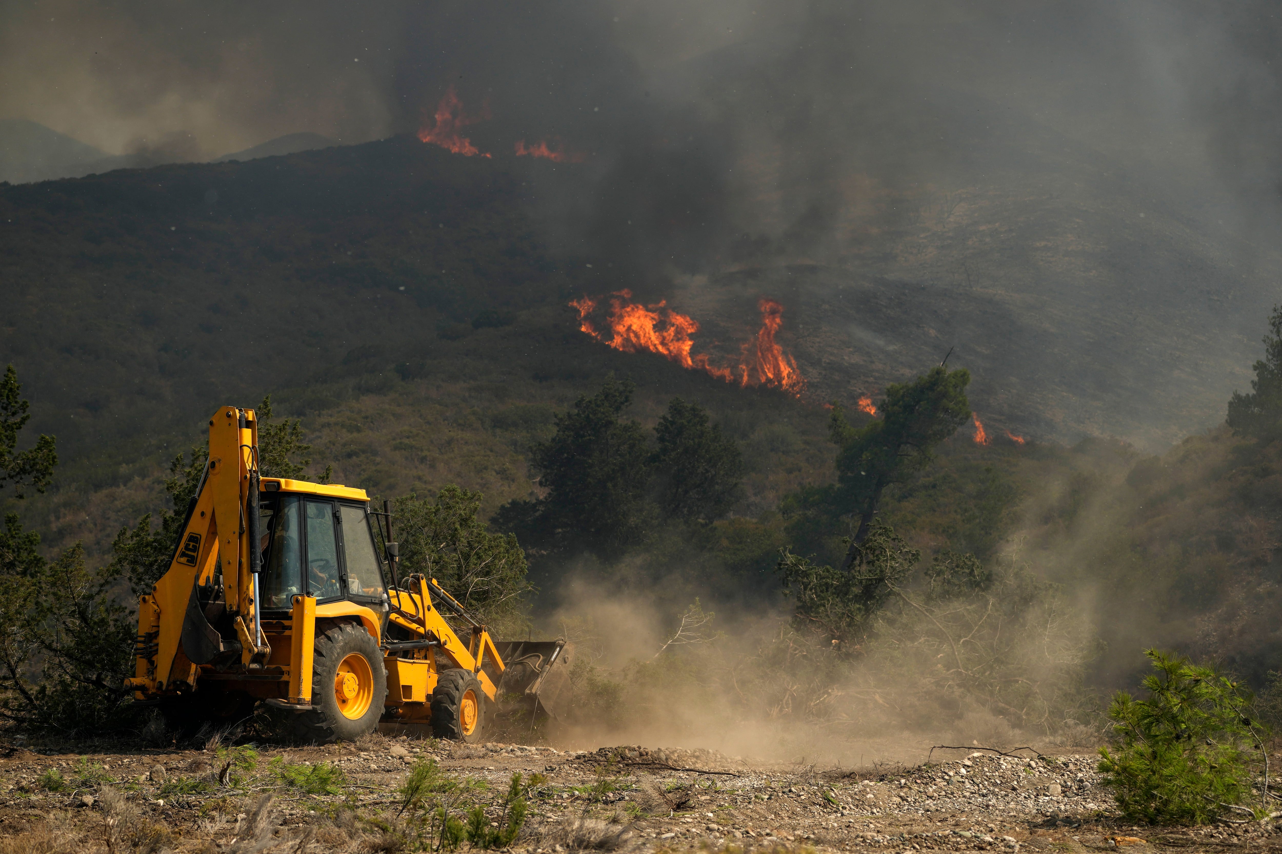 Un bulldozer trabaja en un bosque incendiado en Rodas (AP/Petros Giannakouris)