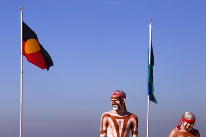 Artistas aborígenes australianos vestidos tradicionalmente junto a una bandera aborigen y otra bandera de los isleños del estrecho de Torres en la playa Coogee de Sídney. REUTERS/David Gray/Archivo