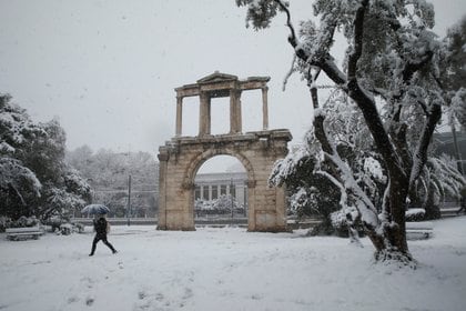 Un paraguas es la única protección para este peatón que circula cerca del Arco de Adriano en Atenas (REUTERS/Costas Baltas)