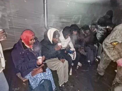 Migrantes se reúnen para tomar una bebida caliente en una tienda de campaña cerca de la frontera con Finlandia en el puesto de control de Salla unos 1.300 km al norte de Moscú, Rusia (AP)