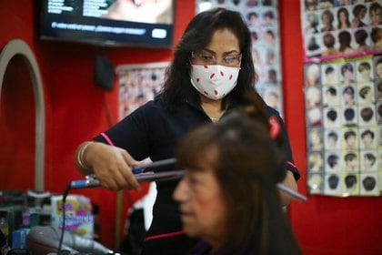 Un peluquero con máscara peina el cabello de una mujer en el salón de belleza "Imagen", mientras continúa la propagación del coronavirus (Foto: Reuters)