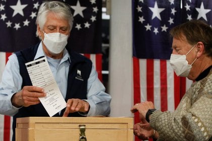 Selectman Les Otten emite una boleta en una urna poco después de la medianoche para las elecciones presidenciales de EE. UU. En Hale House at Balsams Hotel en la aldea de Dixville Notch, New Hampshire, EE. UU., 3 de noviembre de 2020. REUTERS / Ashley L .Conti