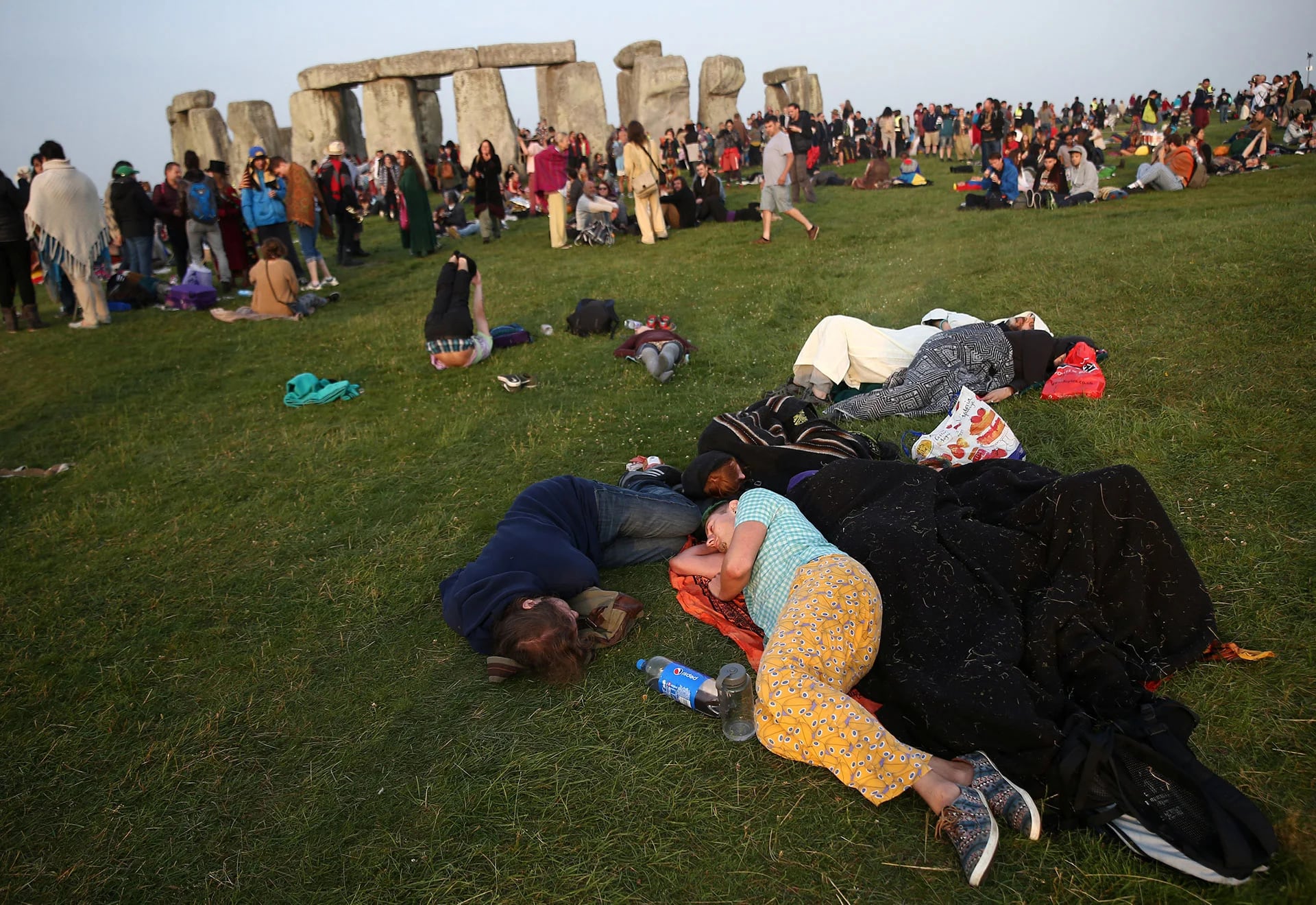 Tras haber esperado toda la noche para ver el amanecer, las personas duermen en el pasto frente a Stonehenge (Reuters)