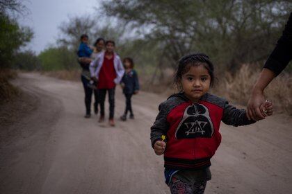 Taznari, una niña migrante hondureña solicitante de asilo de tres años, toma la mano de su madre mientras caminan por un camino de tierra después de cruzar el río Grande hacia Estados Unidos desde México en una balsa en Peñitas, Texas, Estados Unidos, marzo 16 de febrero de 2021 Foto: (REUTERS/Adrees Latif)