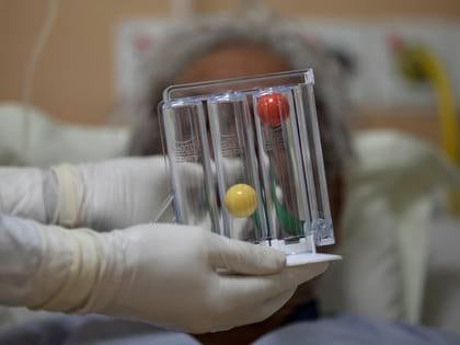 A medical worker helps a patient suffering from the coronavirus disease (COVID-19) to blow a spirometer for increase lung capacity, at the Intensive Care Unit (ICU) of the Max Smart Super Speciality Hospital in New Delhi, India, May 28, 2020. REUTERS/Danish Siddiqui