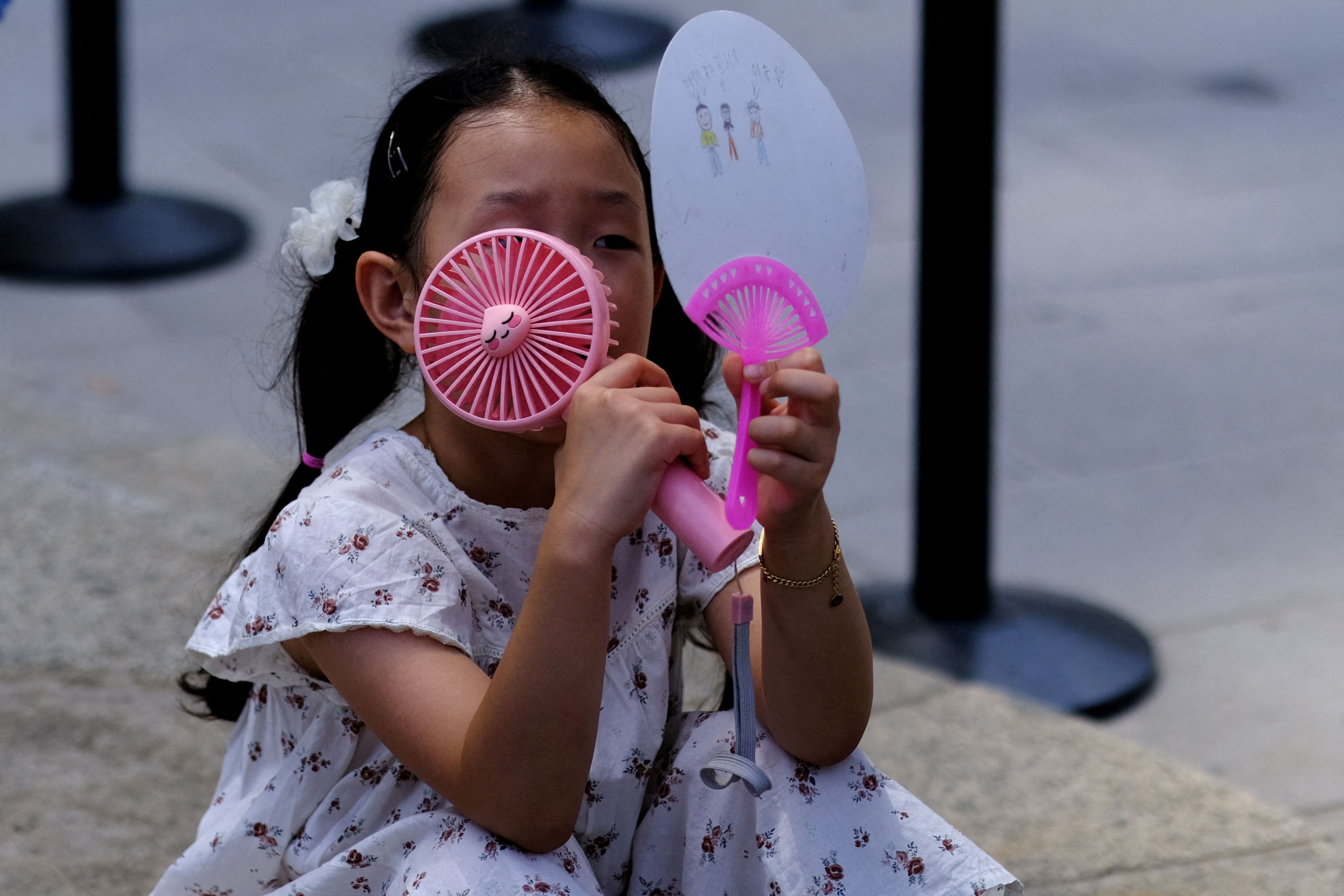 Una niña surcoreana usa abanicos mientras espera con su madre la entrada a la basílica de la Sagrada Familia en Barcelona, mientras Europa se encuentra en alerta roja por la ola de calor, España 18 de julio de 2023. REUTERS/Nacho Doce