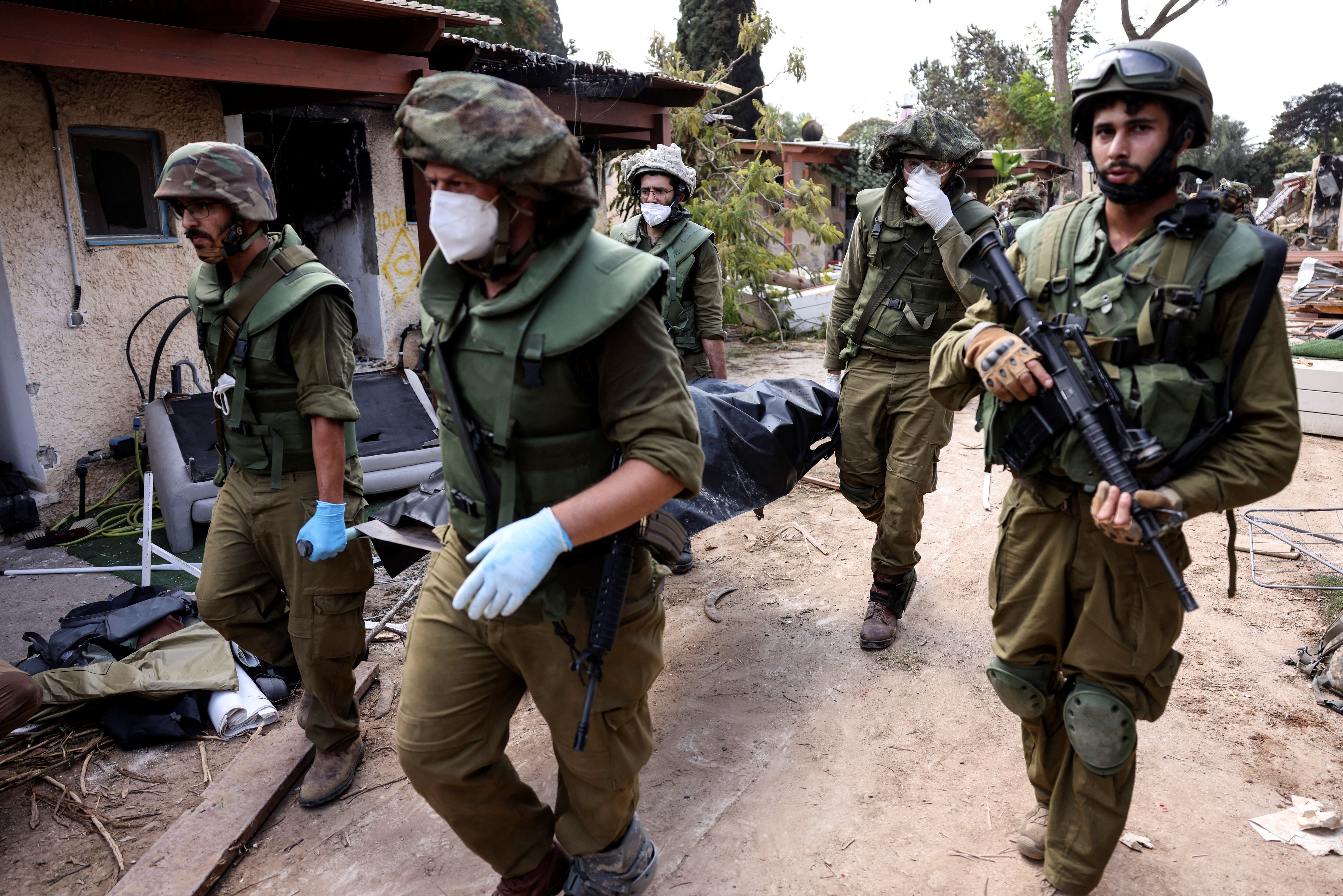 Soldados israelíes llevan un cadáver mientras recogen cuerpos tras los ataques desde Gaza en el kibutz Kfar Aza, en el sur de Israel, 10 de octubre de 2023. REUTERS/Ronen Zvulun