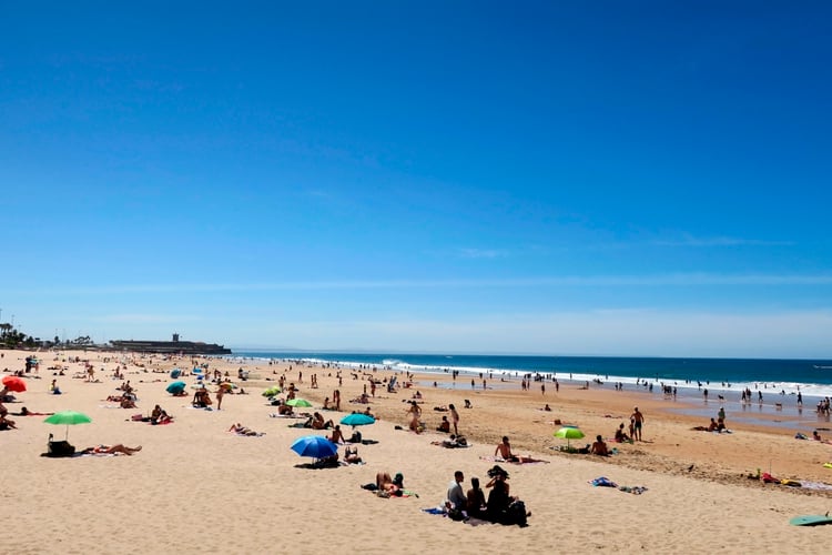 Numerosas personas en la playa de Carcavelos, en la ciudad portuguesa de Cascais. Aunque la temporada de baño no arranca oficialmente hasta el 6 de junio, los portugueses pueden ya pisar la arena en esta fase de la desescalada (EFE) 