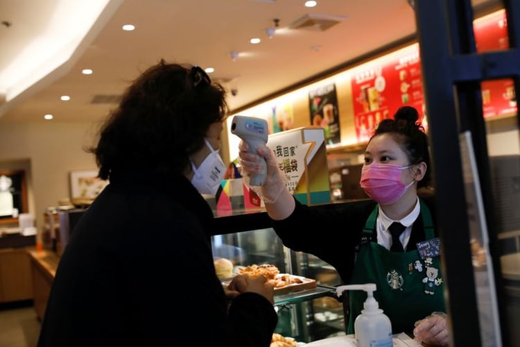 FOTO DE ARCHIVO. Una trabajadora usa un termómetro para chequear la temperatura de una cliente que entra a una tienda de Starbucks, mientras el país es golpeado por un nuevo coronavirus, en Pekín, China. 30 de enero de 2020. REUTERS/Carlos Garcia Rawlins.