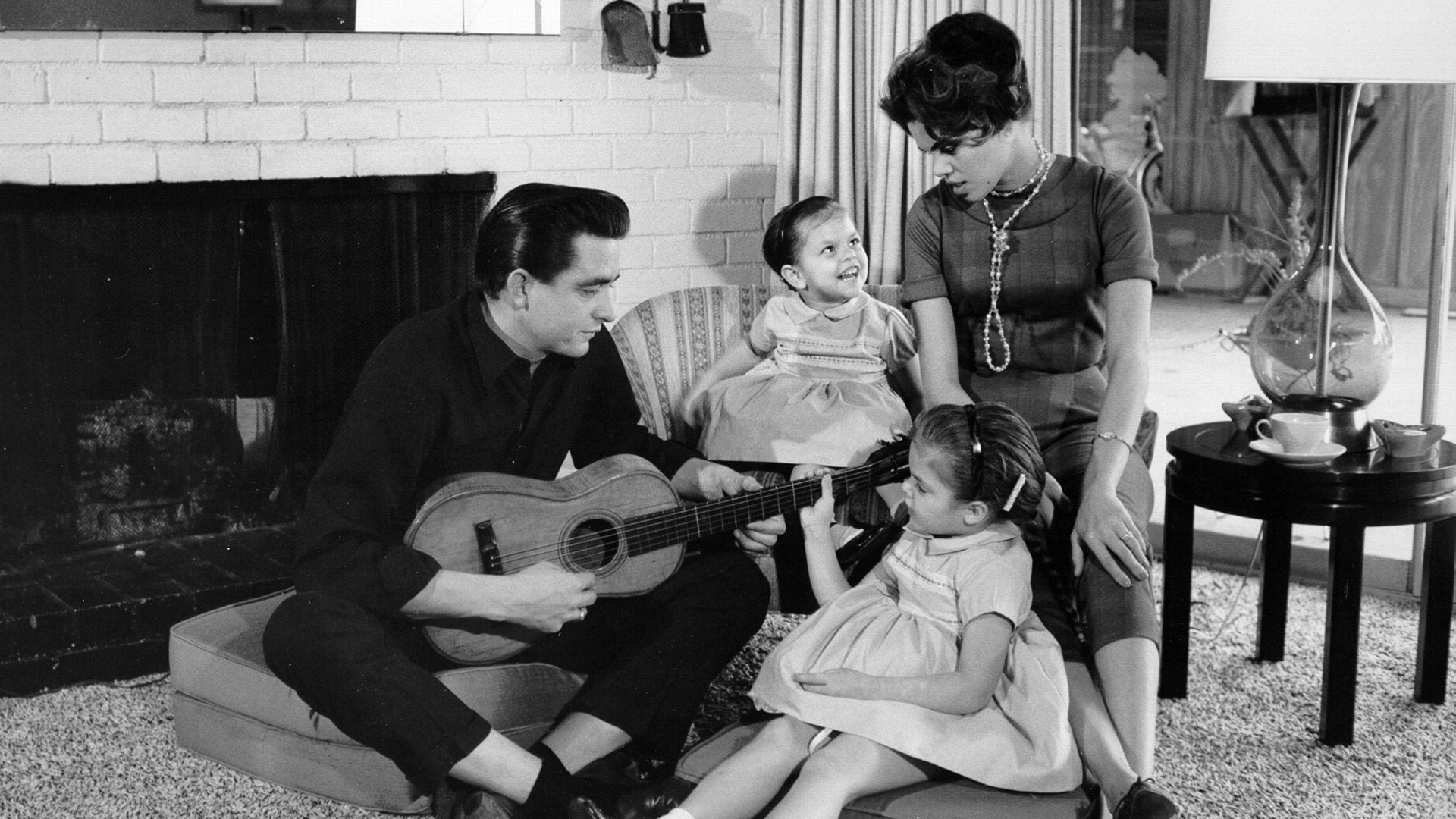 El cantante y compositor de música country Johnny Cash con una guitarra mientras su primera esposa, Vivian Liberto, y sus hijas, Rosanne y Kathy comparten un momento distendido, en 1957 (Michael Ochs Archives/Getty Images)
