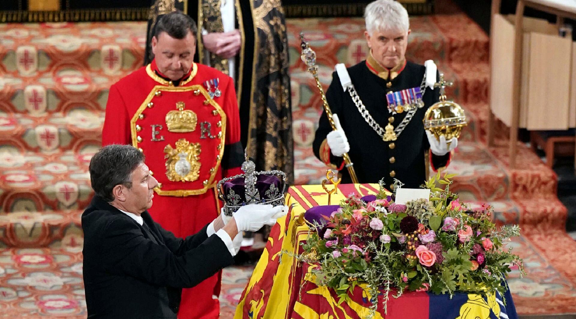 The Crown Jeweller, left, removes the Imperial State Crown from the coffin of Britain's Queen Elizabeth II during a committal service at St George's Chapel, Windsor Castle, in Windsor, England, Monday, Sept. 19, 2022. (Joe Giddens/Pool Photo via AP)