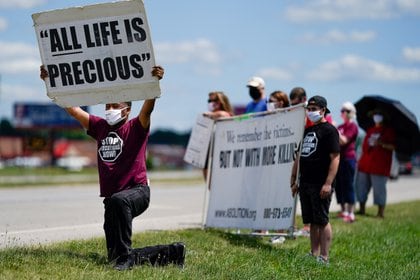 El reverendo Sylvester Edwards se arrodilla mientras otros manifestantes sostienen carteles cerca del Complejo Correccional Federal de Terre Haute, Indiana, para mostrar su oposición a la pena de muerte y la ejecución de Daniel Lewis Lee (REUTERS / Bryan Woolston)