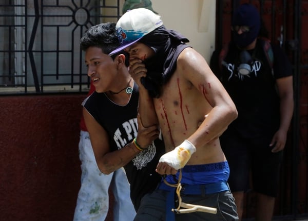 Un manifestante herido en Masaya es ayudado por un compañero en una protesta (AFP)