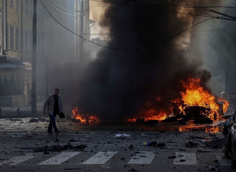 Un hombre camina cerca de su auto quemado tras el ataque militar ruso en el centro de Kiev (REUTERS/Gleb Garanich)