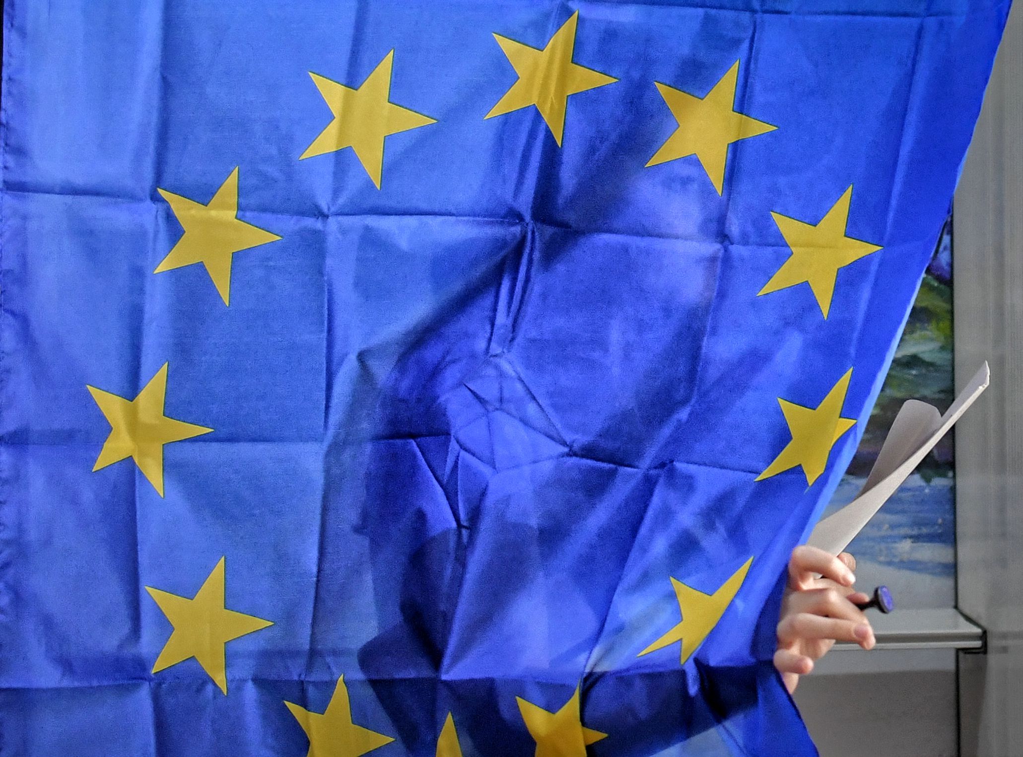 Una mujer sale de una cabina de voto con cortinas que muestran la bandera de la Unión Europea en Baleni, Rumania (AP Foto/Andreea Alexandru)