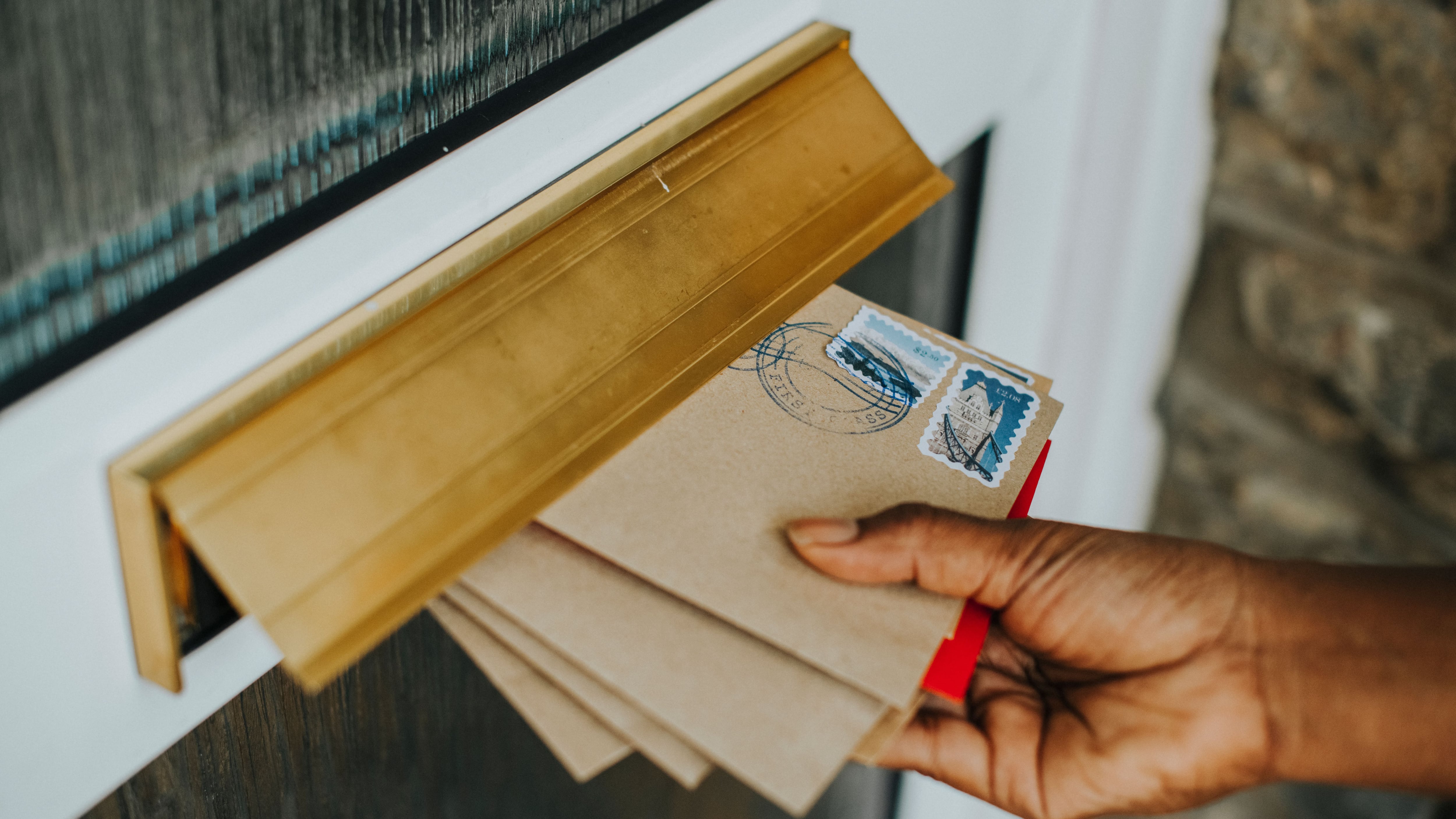 Una mujer cogiendo las cartas del buzón (Freepik)