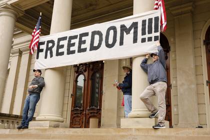 Dos hombres sostienen un cartel con la leyenda "libertad" en la puerta del capitolio (AFP)