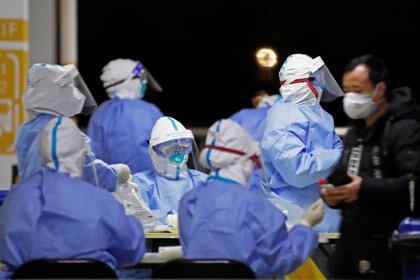 Trabajadores de la salud durante pruebas masivas a trabajadores en el aeropuerto de Pudong (Foto vía REUTERS)