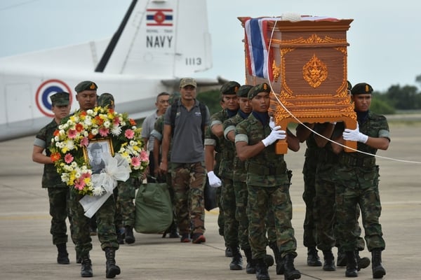 An honour guard carries the coffin of Samarn Kunan, 38, a former member of Thailand’s elite navy SEAL unit who died working to save 12 boys and their soccer coach trapped inside a flooded cave, at an airport in Rayong province, Thailand, July 6, 2018. REUTERS/Panumas Sanguanwong