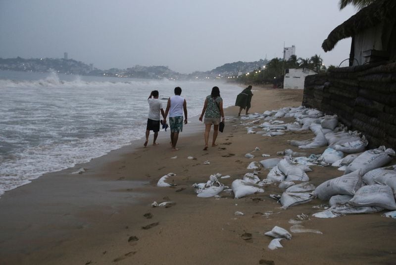 Varias personas caminan por una playa mientras el huracán Otis se dirige hacia Acapulco. (Foto: Reuters)