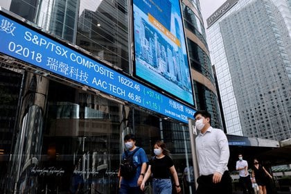 Personas con máscaras en el distrito financiero de Hong Kong.  La actividad económica, a pesar de muchas dificultades, se ha reactivado en gran parte del mundo, desde el peor momento de la pandemia. 
