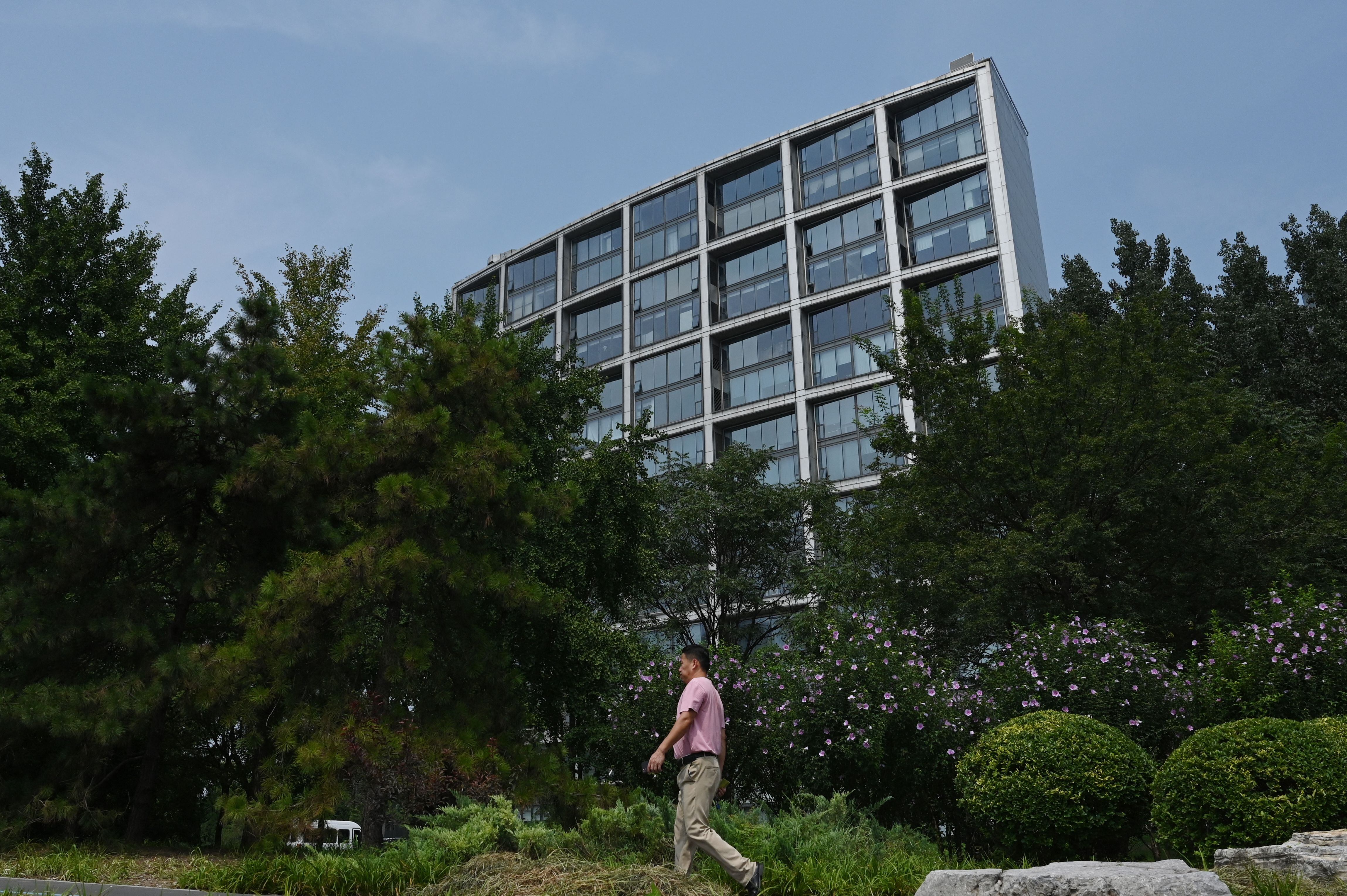 Un hombre camina por un sendero frente a la oficina de Beijing de Zhongrong International Trust (GREG BAKER / AFP)