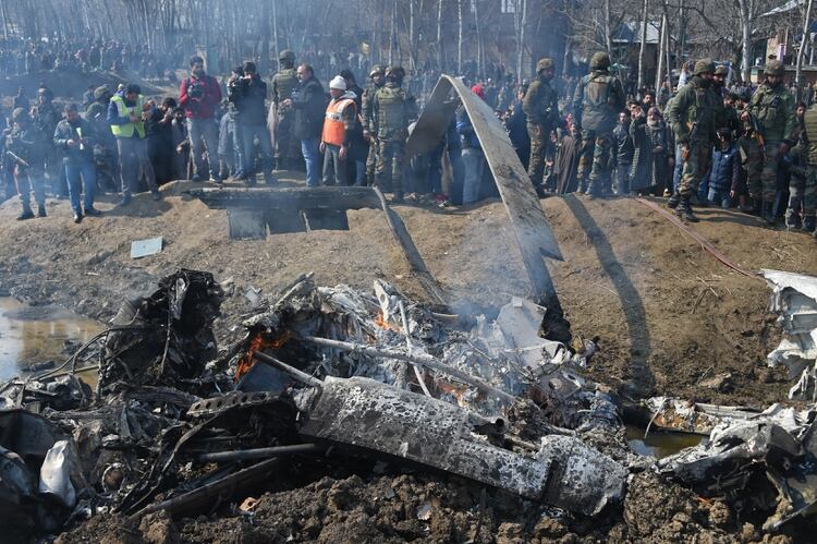 Soldados indios alrededores de los restos de uno de sus helicópteros, que los paquistaníes dicen haber derribado y que Nueva Delhi señala haber perdido por un desperfecto (Photo by Tauseef MUSTAFA / AFP)