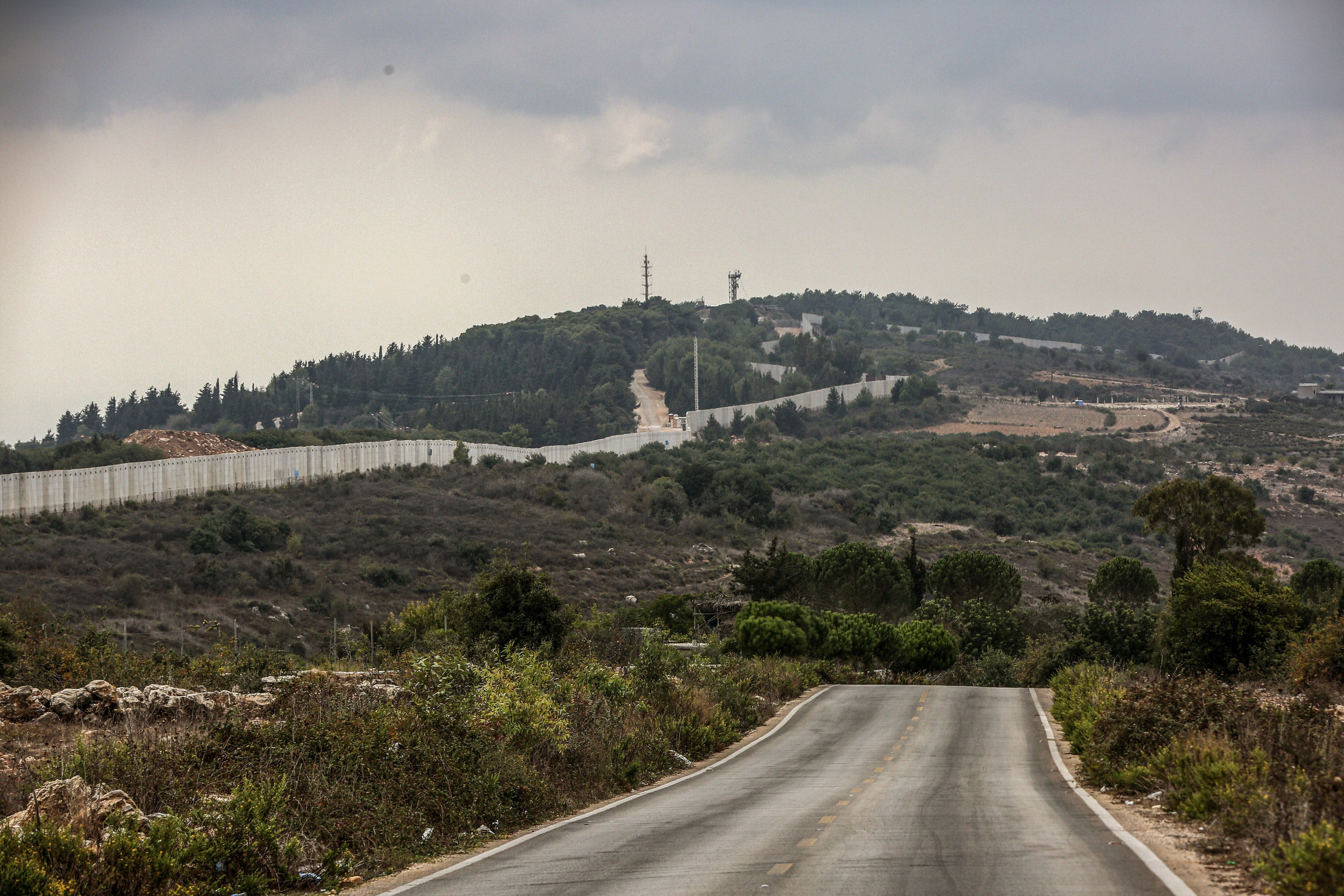 El muro fronterizo erigido por Israel y un puesto militar israelí se ven desde una carretera desierta del pueblo de al Bustan, en la frontera sur libanesa. Foto: Marwan Naamani/dpa/Archivo
