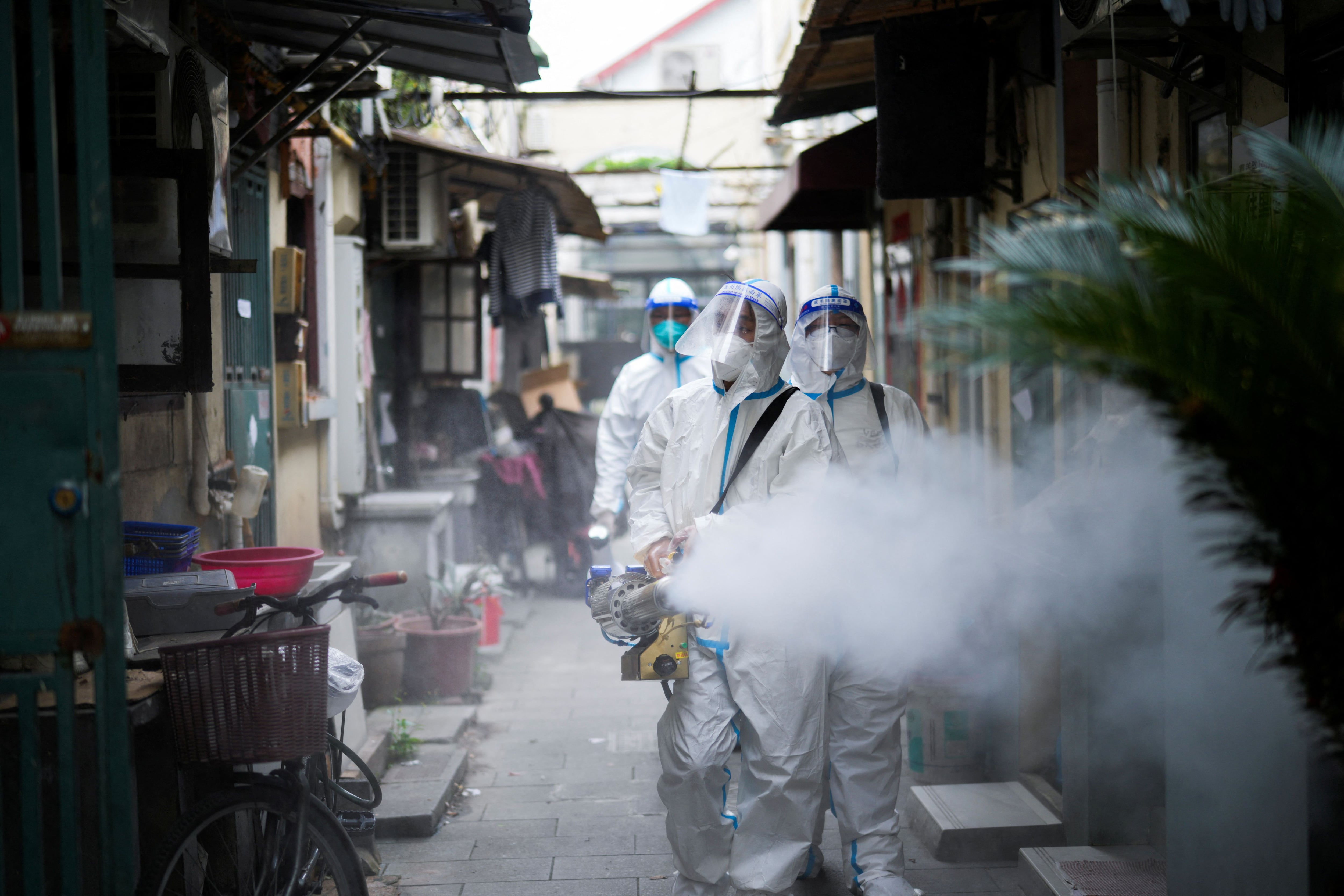 Trabajadores con trajes de protección desinfectan una antigua zona residencial en Shanghái, China, el 15 de abril de 2022. REUTERS/Aly Song