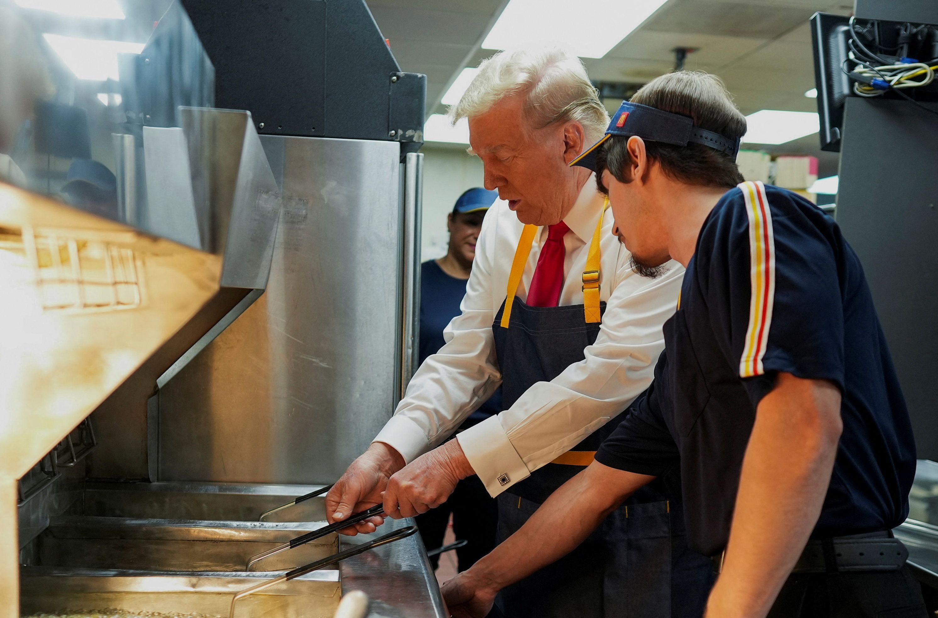 Donald Trump cocinando papas fritas junto a un empleado (Doug Mills/Pool via REUTERS)