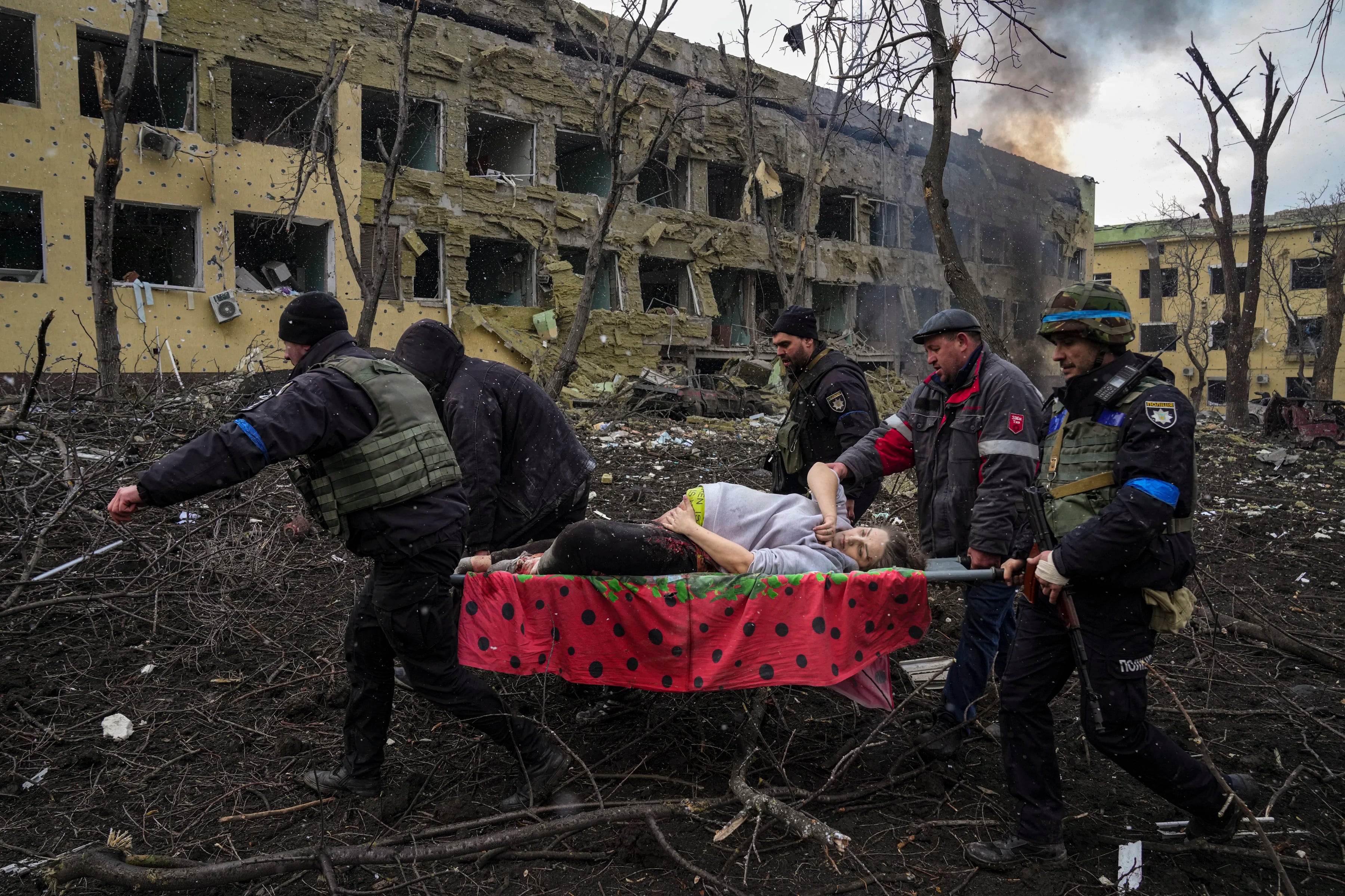 Empleados de emergencia y policías ucranianos evacuan a la mujer embarazada herida Iryna Kalinina, de 32 años, de un hospital de maternidad dañado por un ataque aéreo ruso en Mariupol, Ucrania, el 9 de marzo de 2022. "¡Mátenme ahora!" ella gritó, mientras luchaban por salvar su vida en otro hospital aún más cerca de la línea del frente. El bebé nació muerto y media hora después, Iryna también murió.