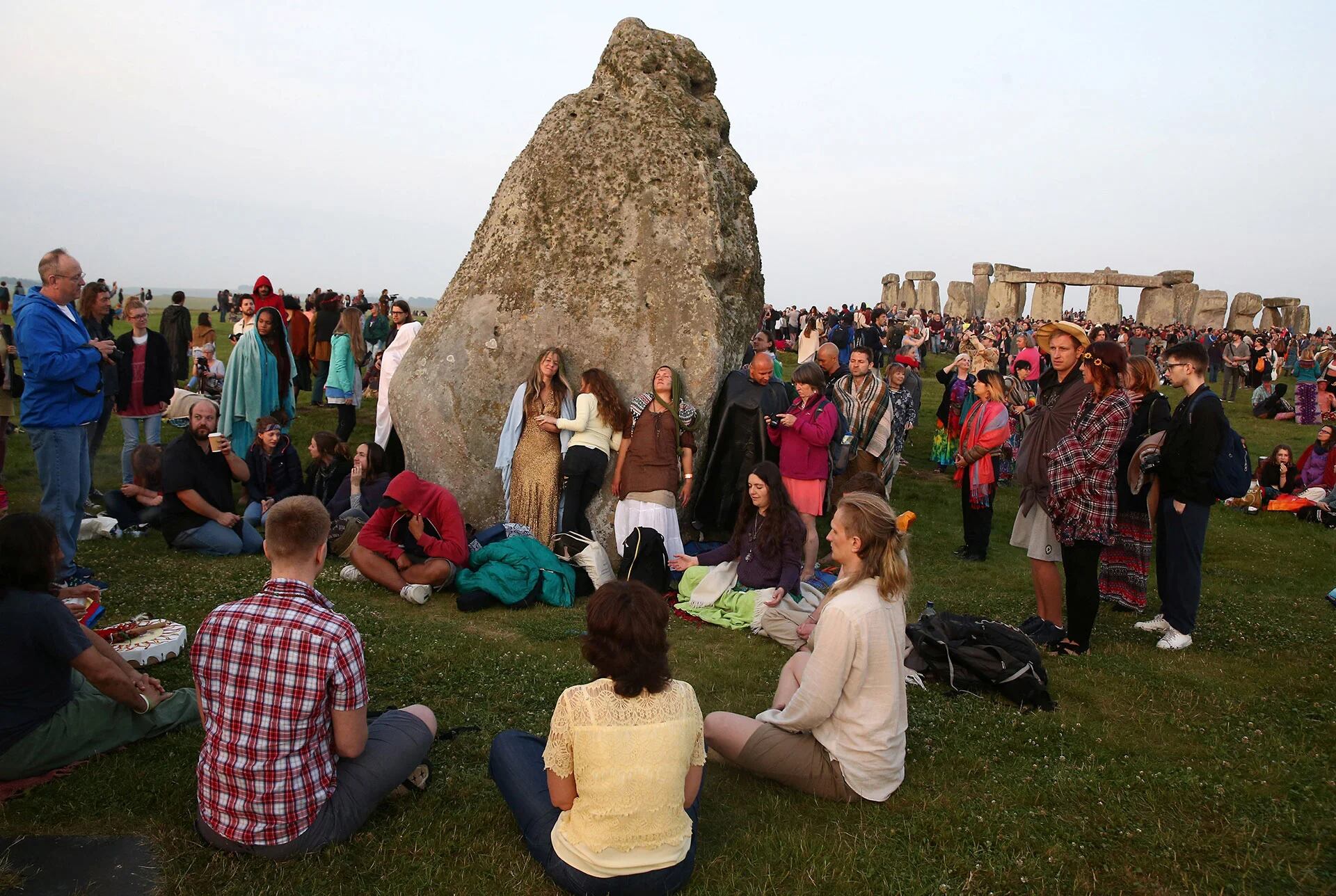 Personas tocando la “Piedra del Tacón”, alineada en dirección al sol naciente durante el solsticio de verano en el hemisferio norte (Reuters)