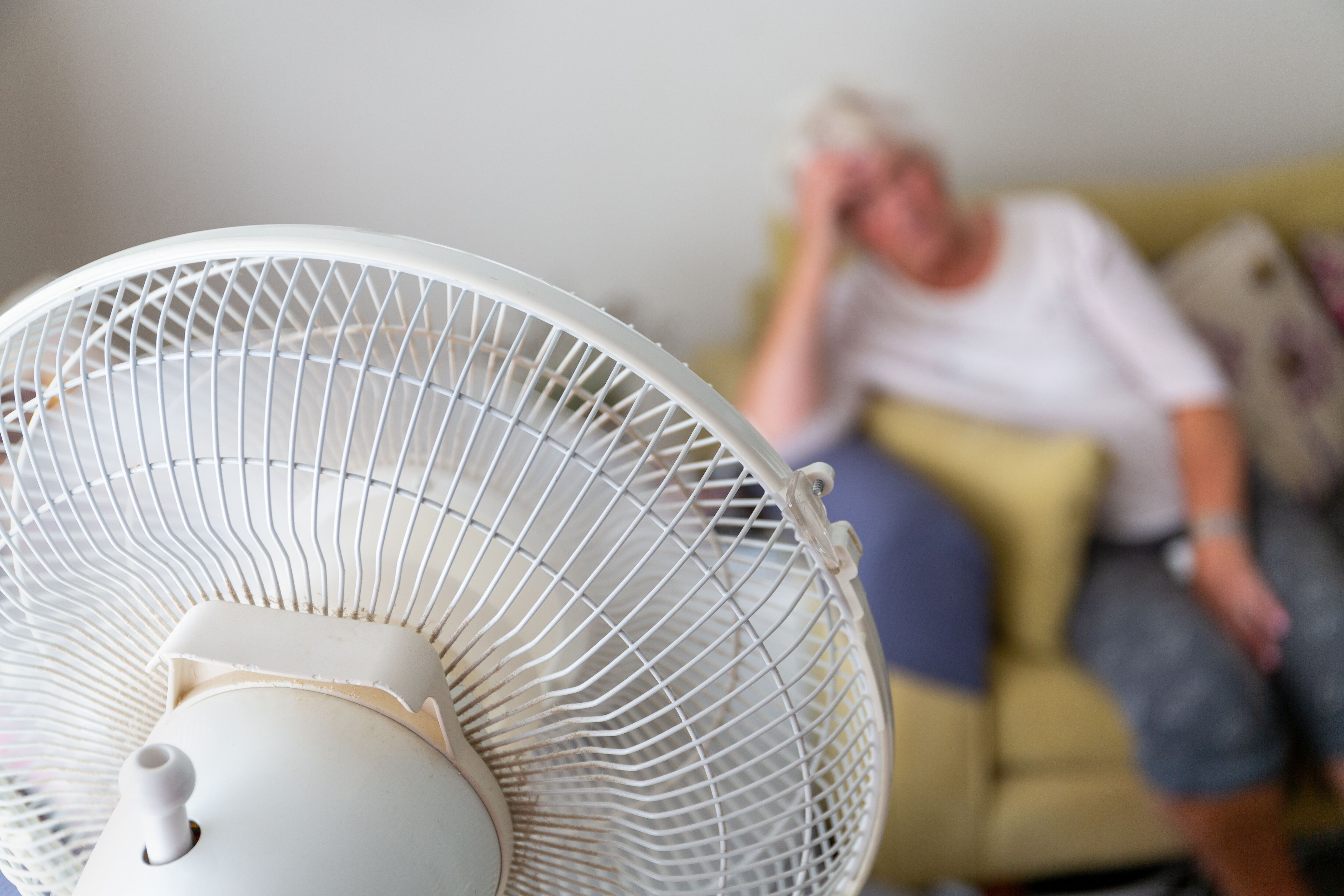 Mujer en el sofá frente a un ventilador (Shutterstock)