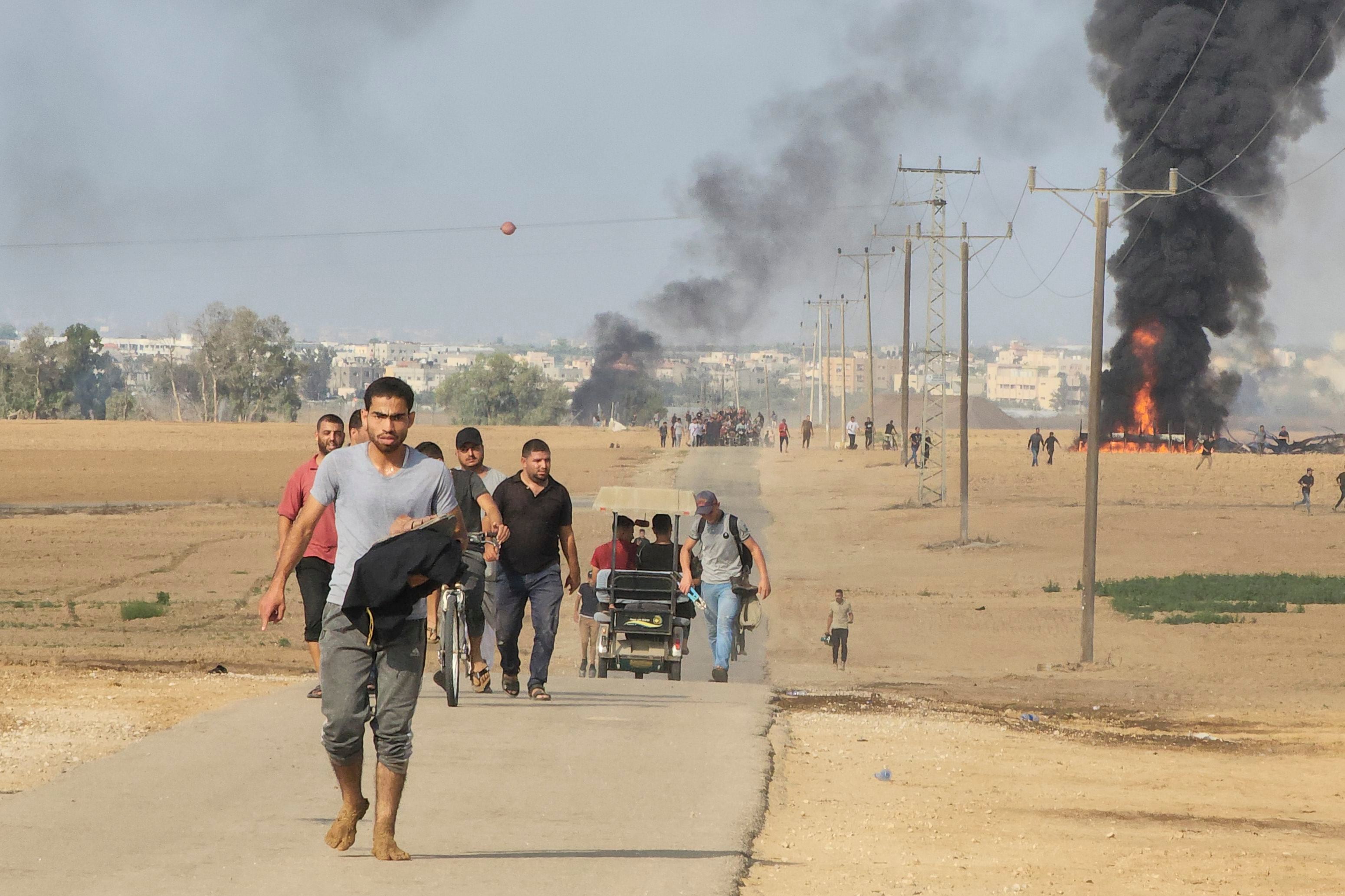 Palestinos se alejan del kibbutz de Kfar Azza, Israel, cerca de la cerca fronteriza de la Franja de Gaza, el 7 de octubre de 2023. (AP Foto/Hassan Eslaiah)