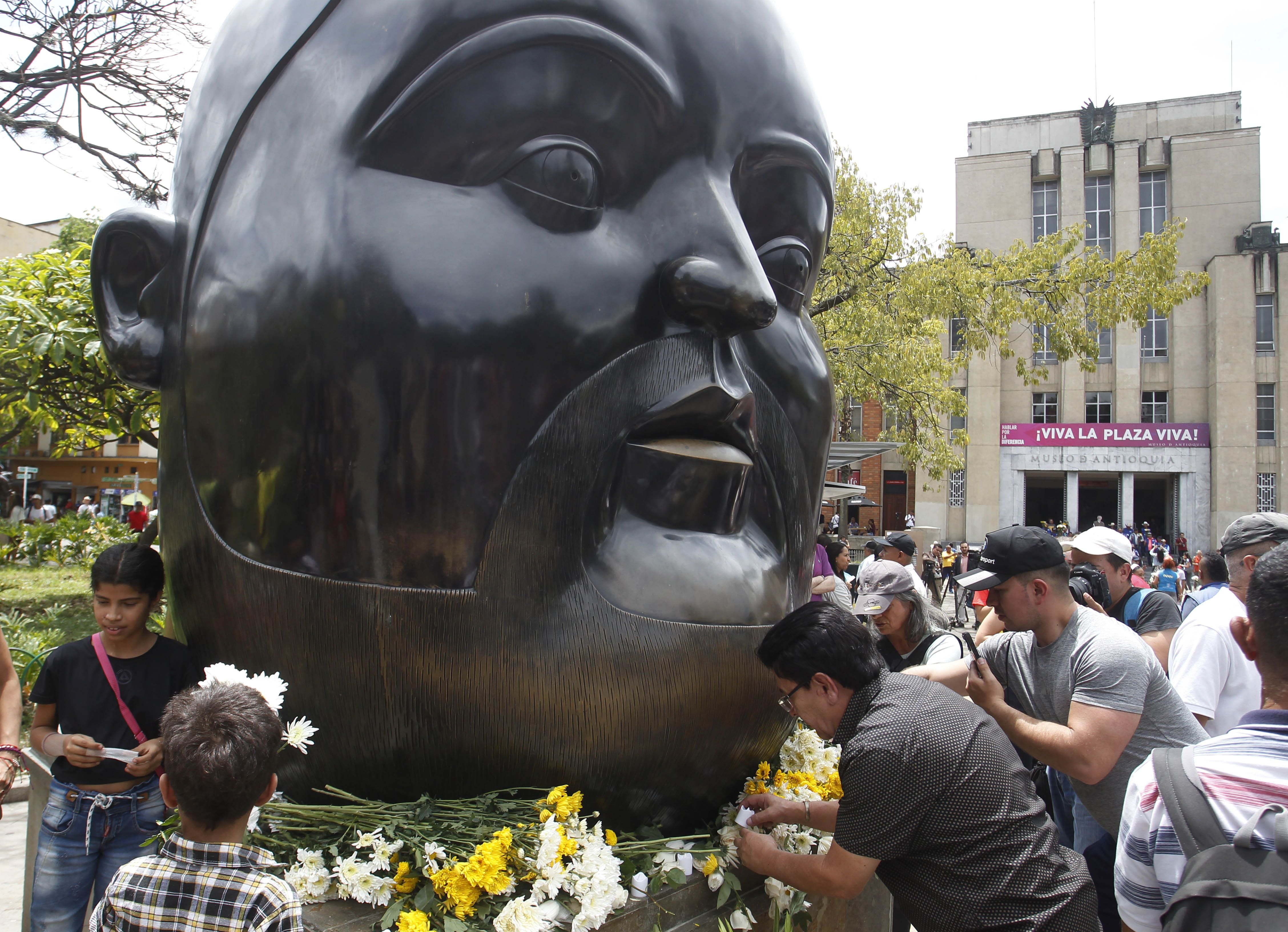 Decenas de personas pusieron ofrendas florales alrededor la escultura "Cabeza", del maestro Fernando Botero, en la icónica Plaza Botero, en Medellín - crédito Luis Noriega/EFE
