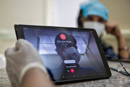 Un trabajador de la salud llama a la unidad de cuidados intensivos para conectar a una paciente con coronavirus con su nieta, usando una instalación de video llamada proporcionada por las autoridades en el hospital LNJP de Nueva Delhi, India (REUTERS/Danish Siddiqui)