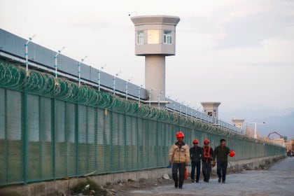 Los trabajadores caminan por el perímetro de lo que el régimen chino llama un campo de educación vocacional, pero que es ampliamente considerado un campo de concentración y trabajo forzado para miembros de la minoría uigur.  Foto: REUTERS / Thomas Peter