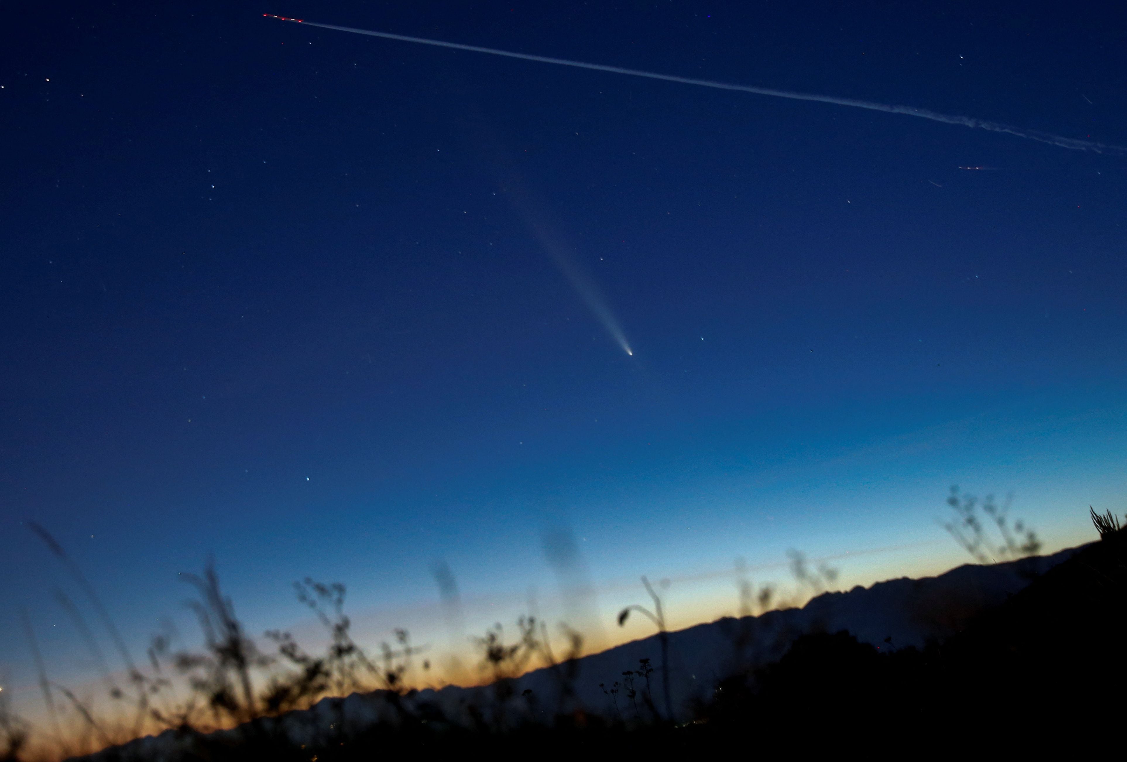 Un satélite deja un rastro de luz cerca de la cola del cometa C/2023 A3 (Tsuchinshan-ATLAS), con una órbita de 80.000 años, conocido como el cometa del siglo, después del atardecer cerca de Skopje, Macedonia del Norte, el 14 de octubre de 2024 REUTERS/Ognen Teofilovski