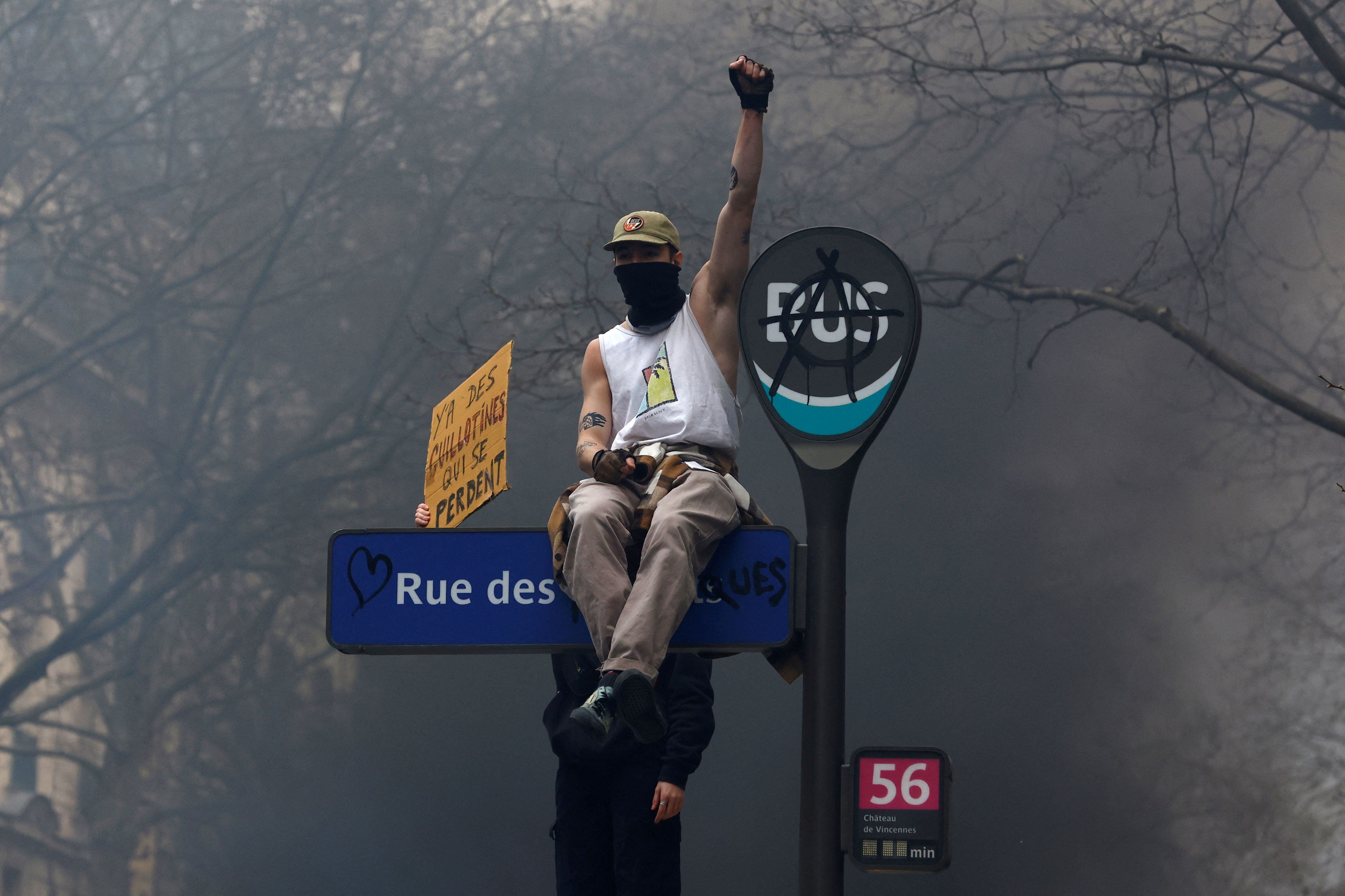 Un manifestante enmascarado trepado al cartel de la intersección de calles en París (REUTERS/Gonzalo Fuentes)