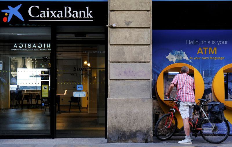 FOTO DE ARCHIVO: Una persona en un cajero automático junto a una sucursal de Caixabank en Barcelona, España, el 3 de octubre de 2022. REUTERS/Nacho Doce