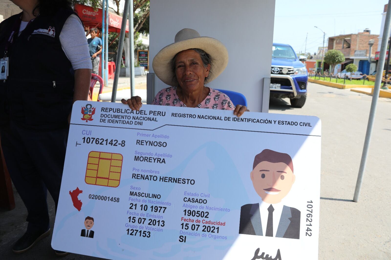 Una mujer sostiene en sus manos una gigantografía de un DNI electrónico, a la espera de hacer su trámite a cero costo para obtener el documento de identidad.