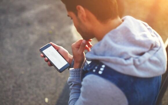 Un hombre joven observa la pantalla de su celular - Ghosting (El Colombiano)