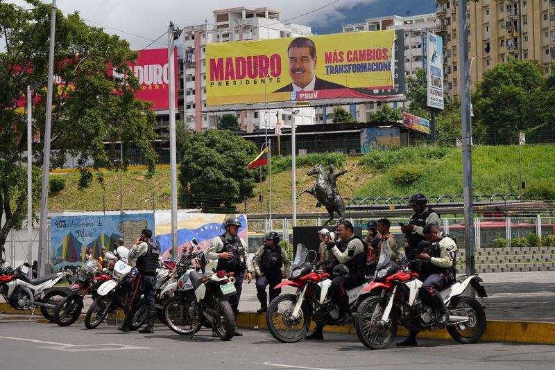 Agentes de policía junto a una valla publicitaria con una imagen de Maduro en Caracas el 31 de julio de 2024 (REUTERS)